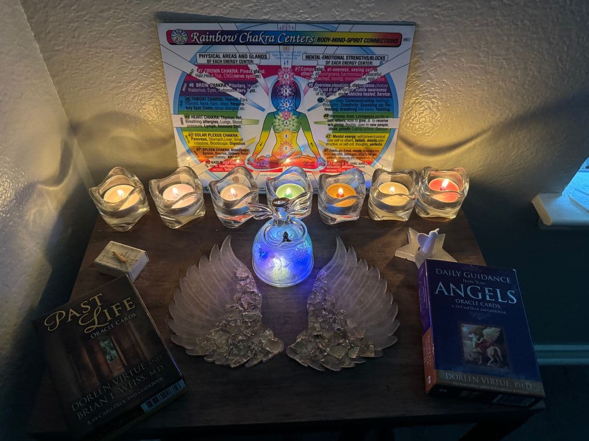 A chakra altar set with seven candles, oracle decks, and a luminous angel, prepared for a workshop session